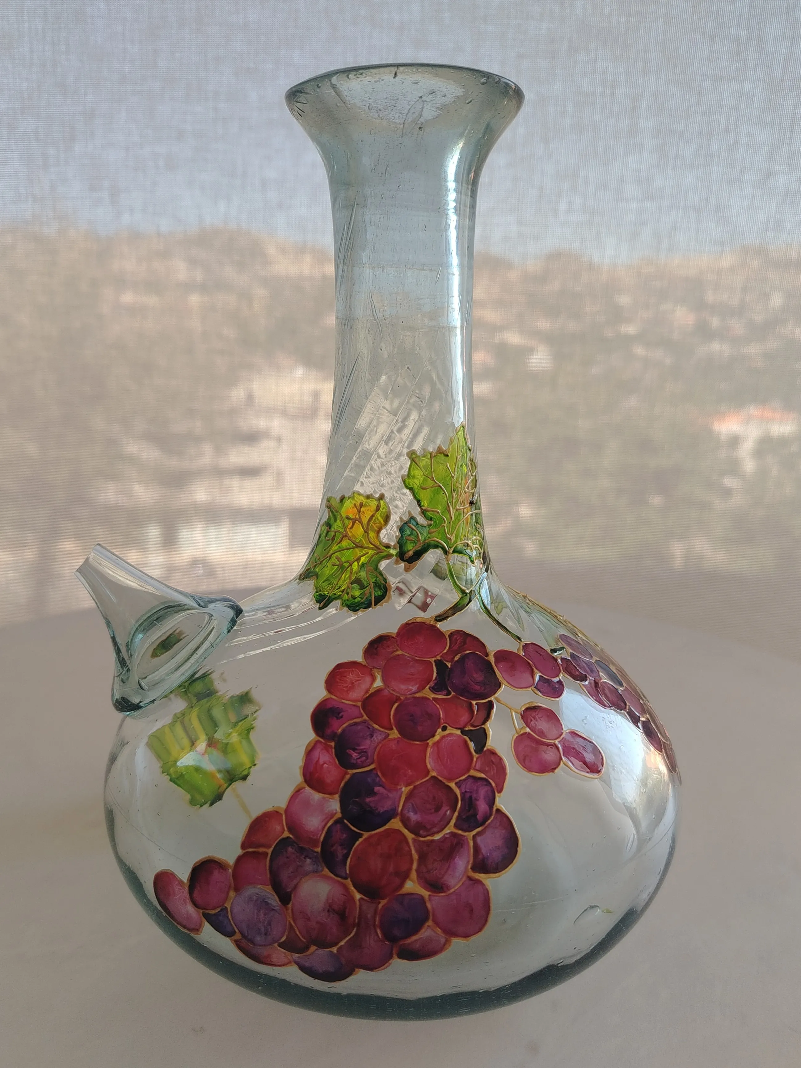 Backlit hand-painted glass jug with deep purple grape clusters and gold vines